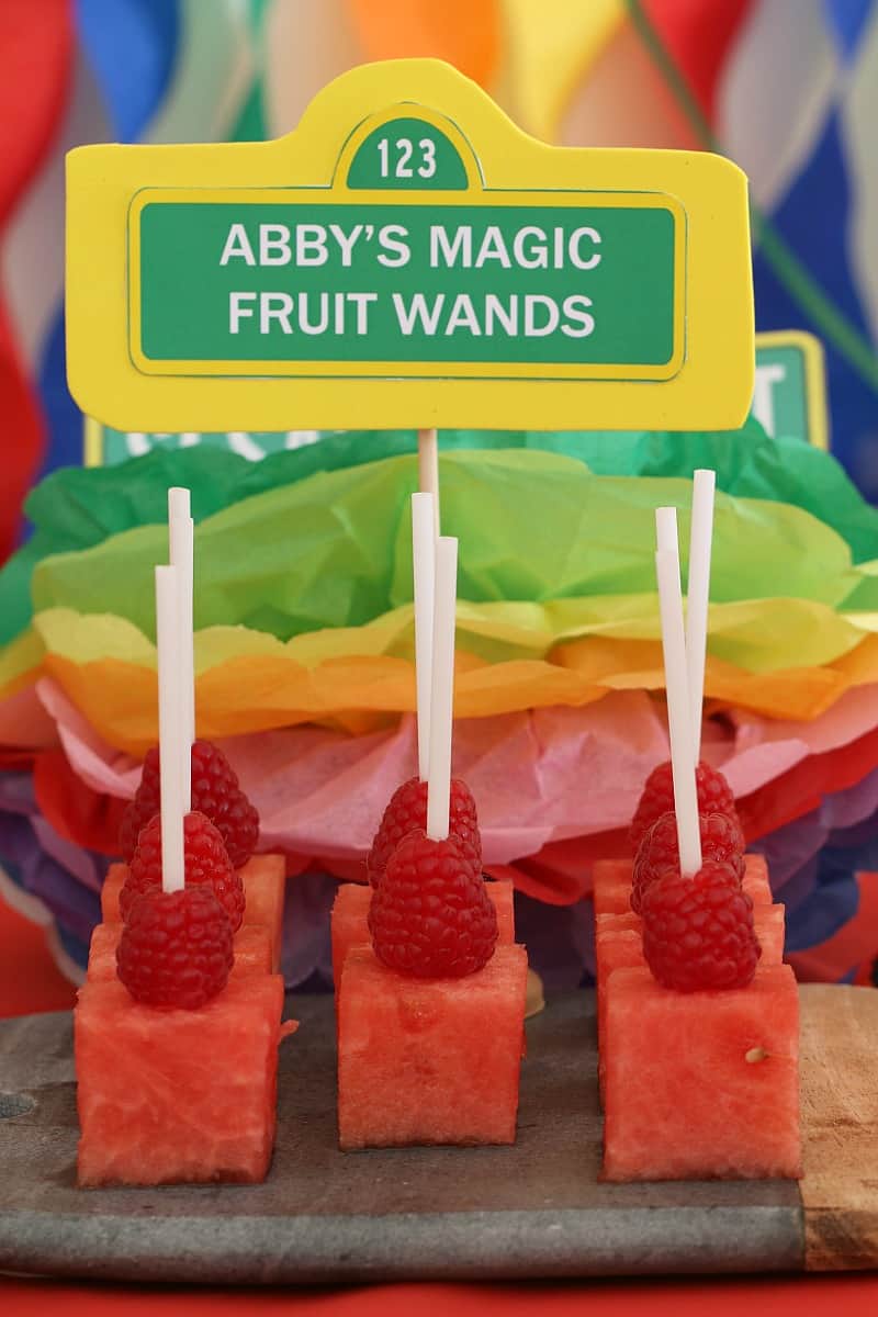 Lollipops made with squares of watermelon with a raspberry on top and a sign saying Abby\'s Magic Fruit Wands