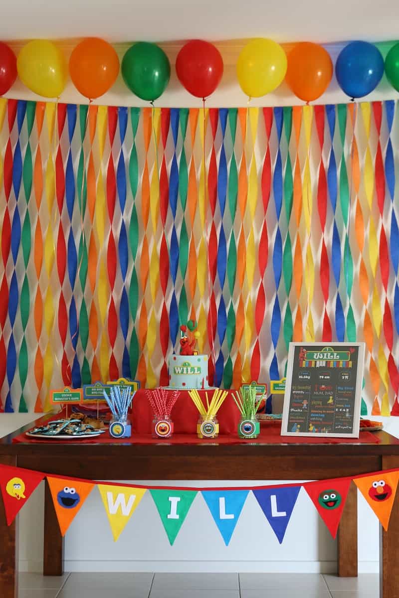 Colouful streamers behind a table with colourful party food for a Sesame Street party