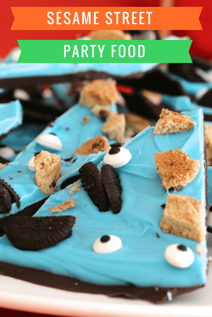 A close up of chocolate bark wedges with a top layer of blue candy, decorated with broken Oreo and chop chip biscuits and edible eyes