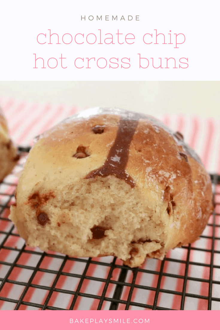 A close up of a Hot Cross Bun made with chocolate chips, sitting on a wire tray