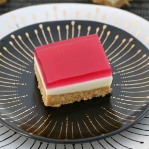 A piece of pink jelly slice on a black plate