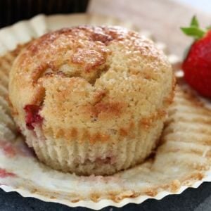 A close up of a muffin made with strawberries, banana and yoghurt, with the muffin case peeled down
