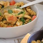 A bowl of chicken pasta with creamy pesto, tomatoes and spinach.