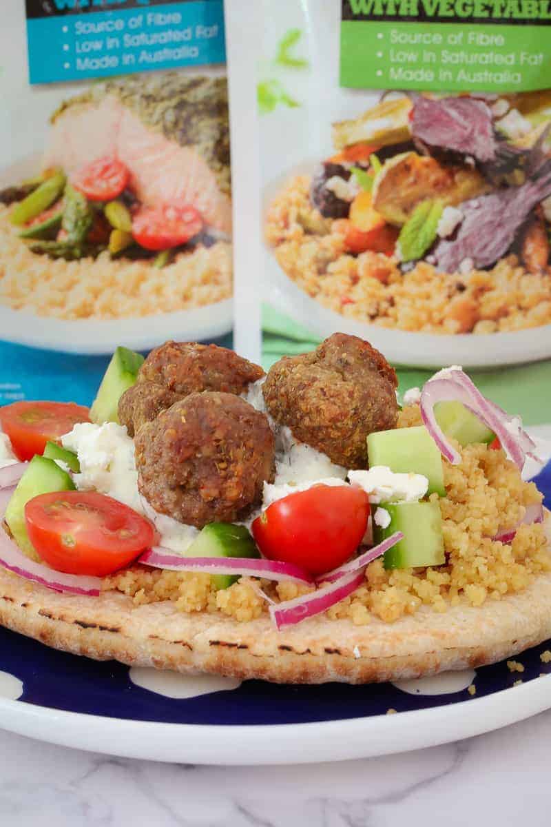 These super yummy oven baked Greek Lamb Meatball Pitas are the perfect family dinner! Top with couscous, cucumber, tomatoes, feta, red onion and tzatziki for a meal everyone will love.