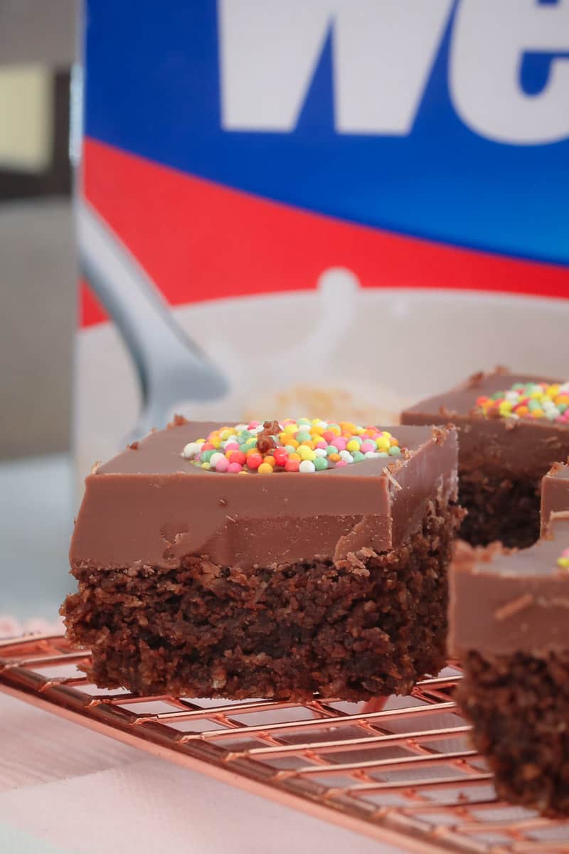 A close up side view of a chocolate slice with a milk chocolate topping and decorated with a coloured Freckle