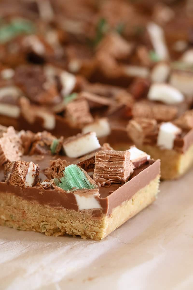 Squares of a biscuit base slice, with a layer of chocolate and chopped peppermint chocolates on top
