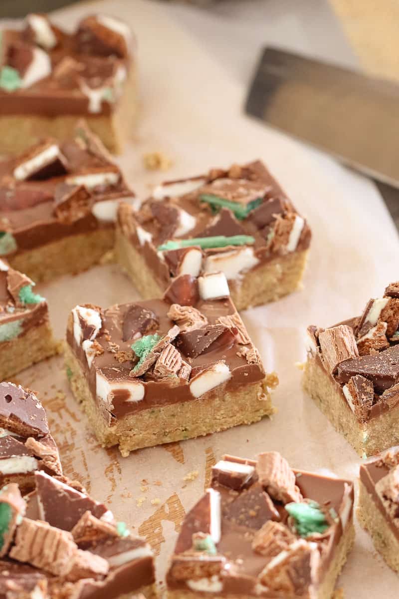 Squares of a biscuit base slice topped with a layer of chocolate and then chopped peppermint chocolates 