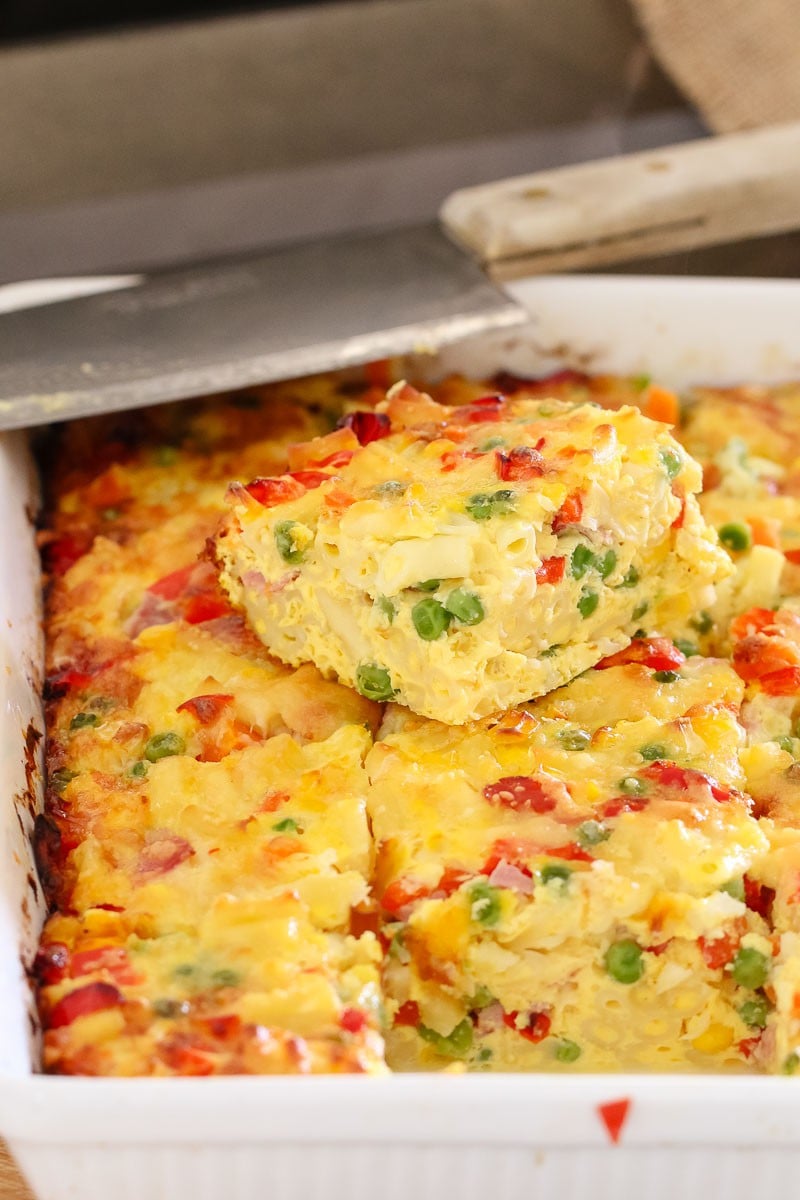 A baking dish filled with cooked frittata showing a filling of eggs, macaroni and vegetables