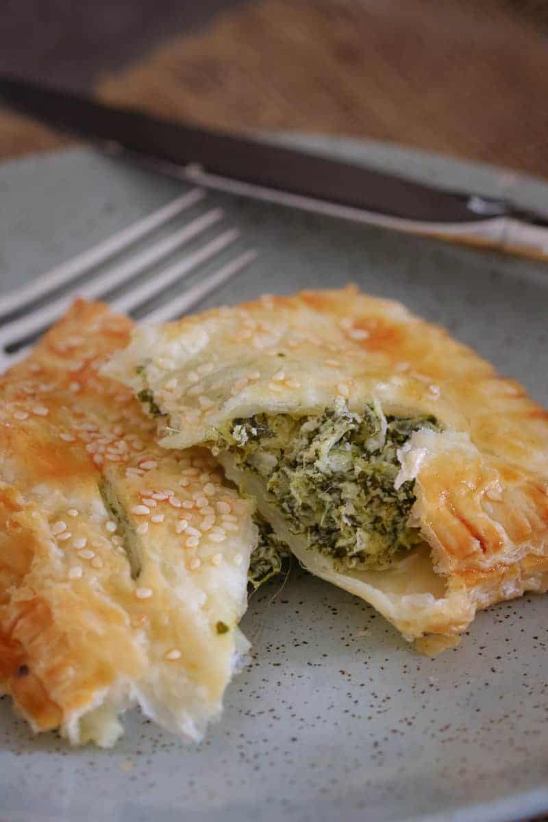 A close up of a golden pastry, split to reveal a filling of spinach and ricotta