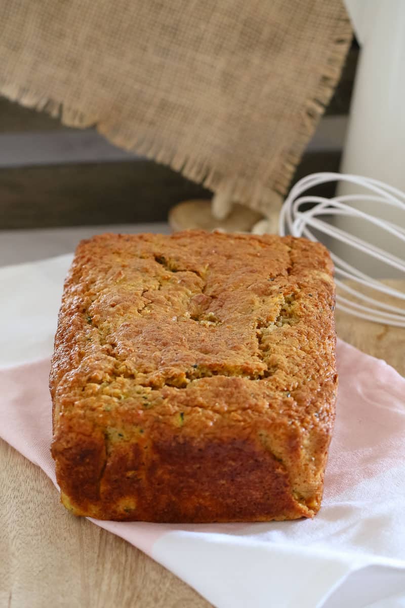An uncut Apple, Zucchini and Carrot loaf on a wooden board