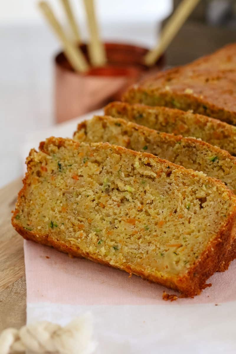 A loaf of Apple, Zucchini and Carrot bread with some slices cuts showing texture
