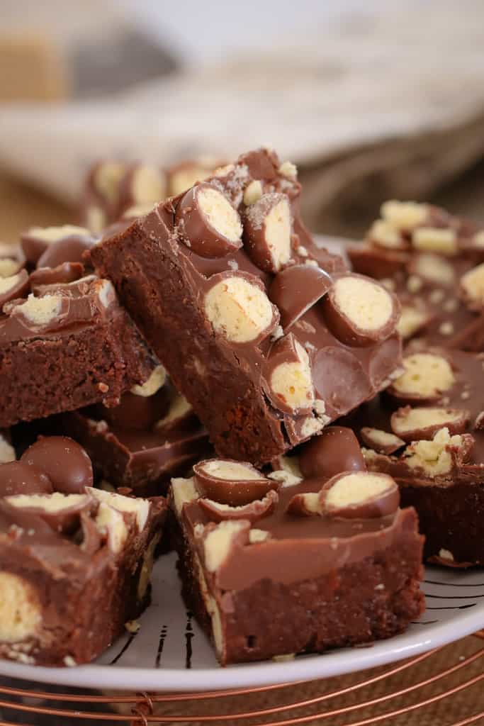 A stack of pieces of chocolate slice topped, with Maltesers and Caramello chocolate