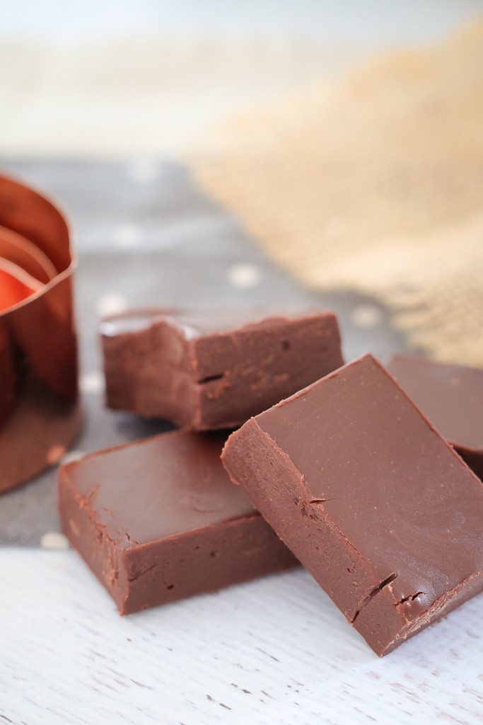 A stack of chocolate fudge squares next to a copper measuring cup