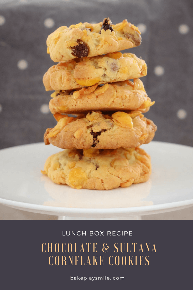 A stack of 5 cornflake cookies with chocolate chips and sultanas on a white plate. 