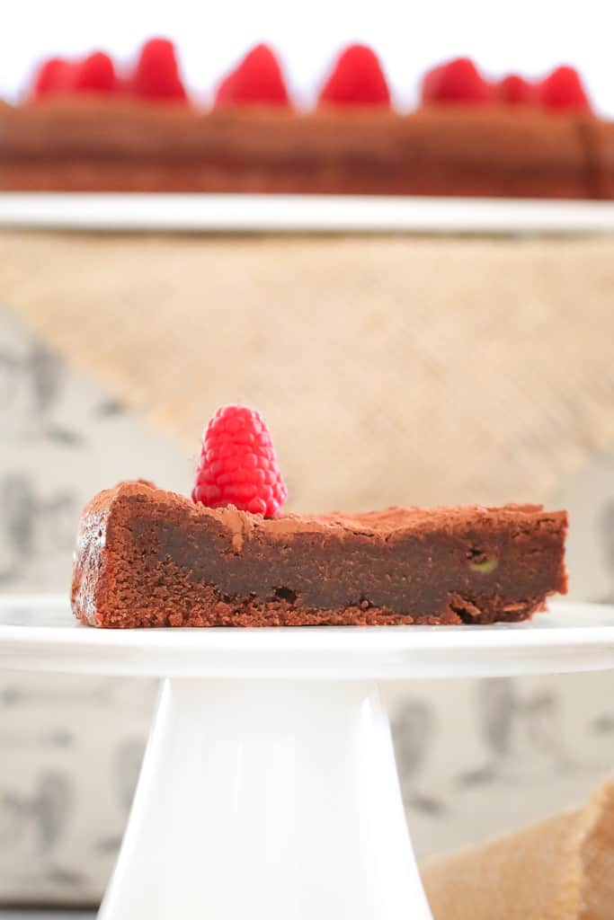 A side view of a slice of a dense, fudgy chocolate torte