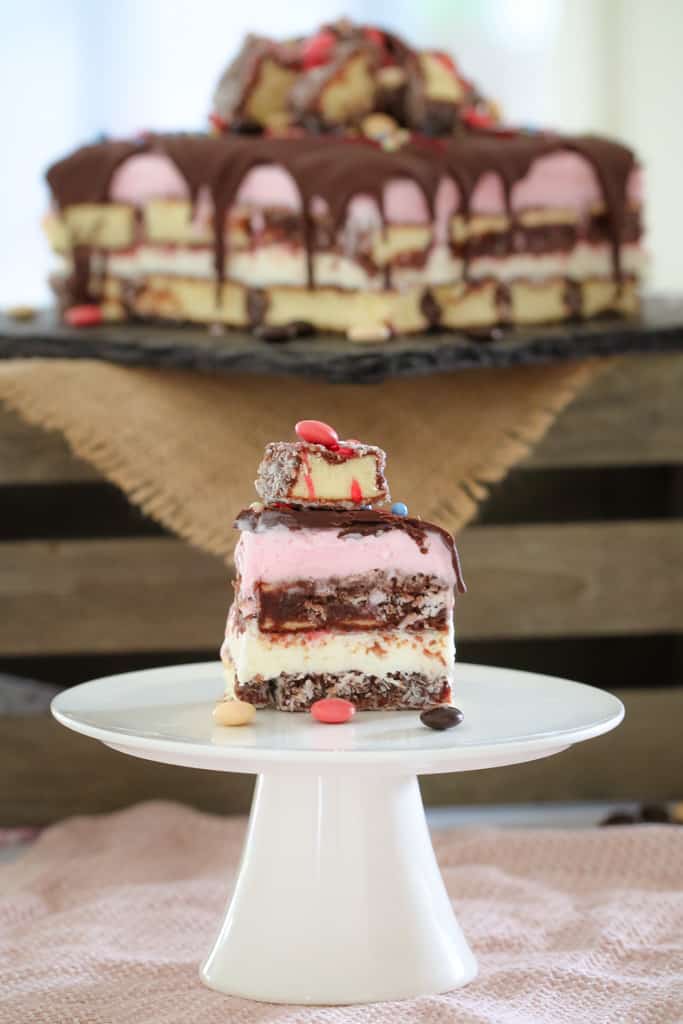 A serve of layered lamington ice cream cake on a white cake stand