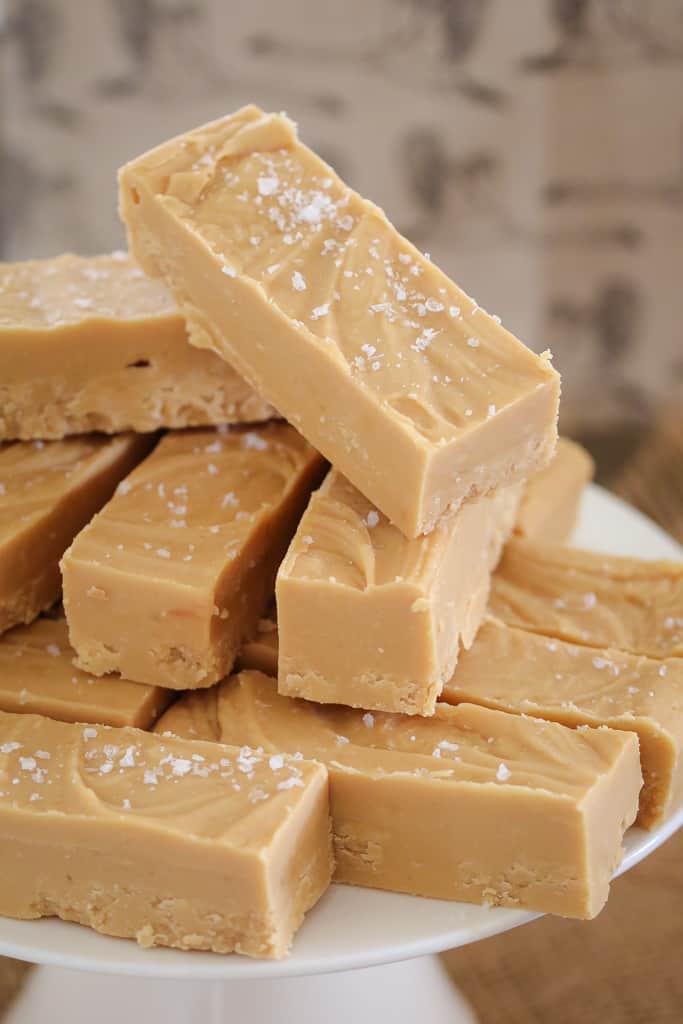 Pieces of caramel fudge sprinkled with sea salt stacked in a pile.