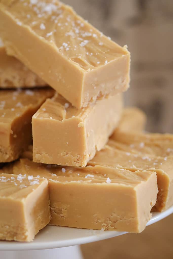 Pieces of salted caramel fudge on a white cake stand. 