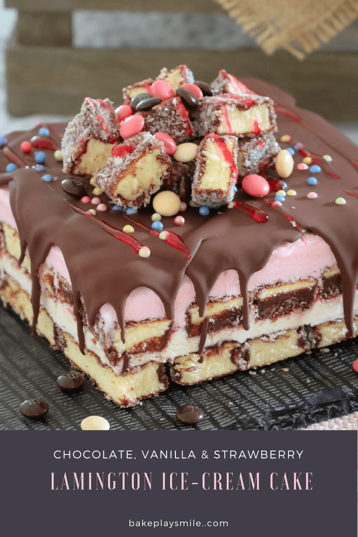 A layered lamington ice cream cake, drizzled with chocolate and raspberry topping, with cut lamington fingers and M&M\'s on top