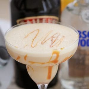 A close up of a creamy cocktail with caramel swirls in a cocktail glass