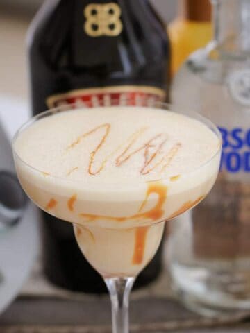 A close up of a creamy cocktail with caramel swirls in a cocktail glass