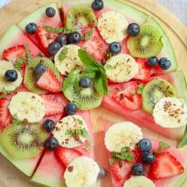This healthy Watermelon Pizza topped with fresh berries, sliced banana, kiwi fruit, creamy passionfruit yoghurt and grated chocolate is the perfect kid-friendly treat.