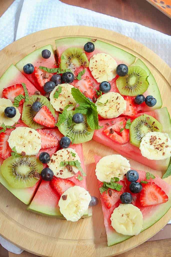 This healthy Watermelon Pizza topped with fresh berries, sliced banana, kiwi fruit, creamy passionfruit yoghurt and grated chocolate is the perfect kid-friendly treat. 