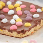 The easiest No-Bake Easter Egg Slice you'll ever make! A biscuit base filled with your favourite mini Easter eggs, topped with a chocolate layer and even more Easter eggs!