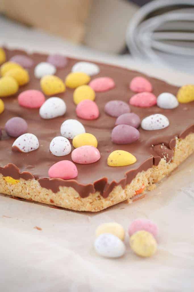 Easter eggs on top of a cookie base slice with milk chocolate topping. 