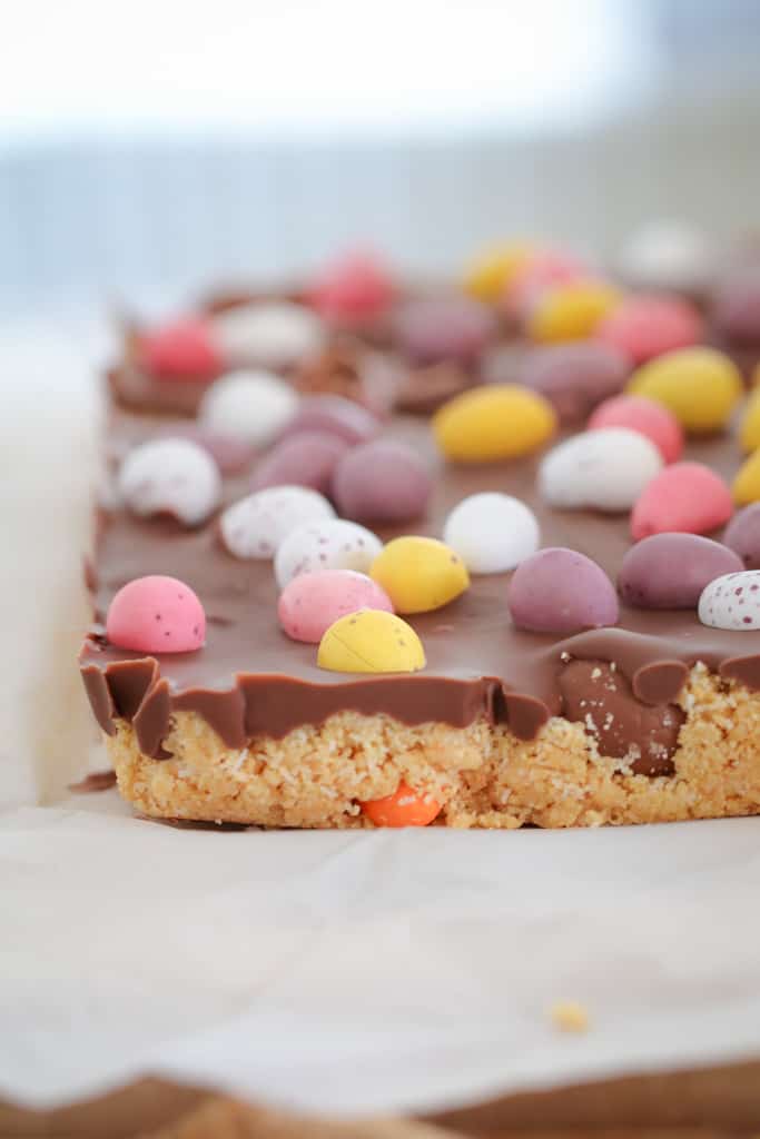 A chocolate slice on white baking paper with chocolate eggs. 