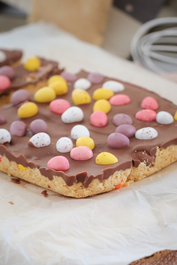 An easter slice made with crushed biscuits and condensed milk, a chocolate layer and Easter eggs. 