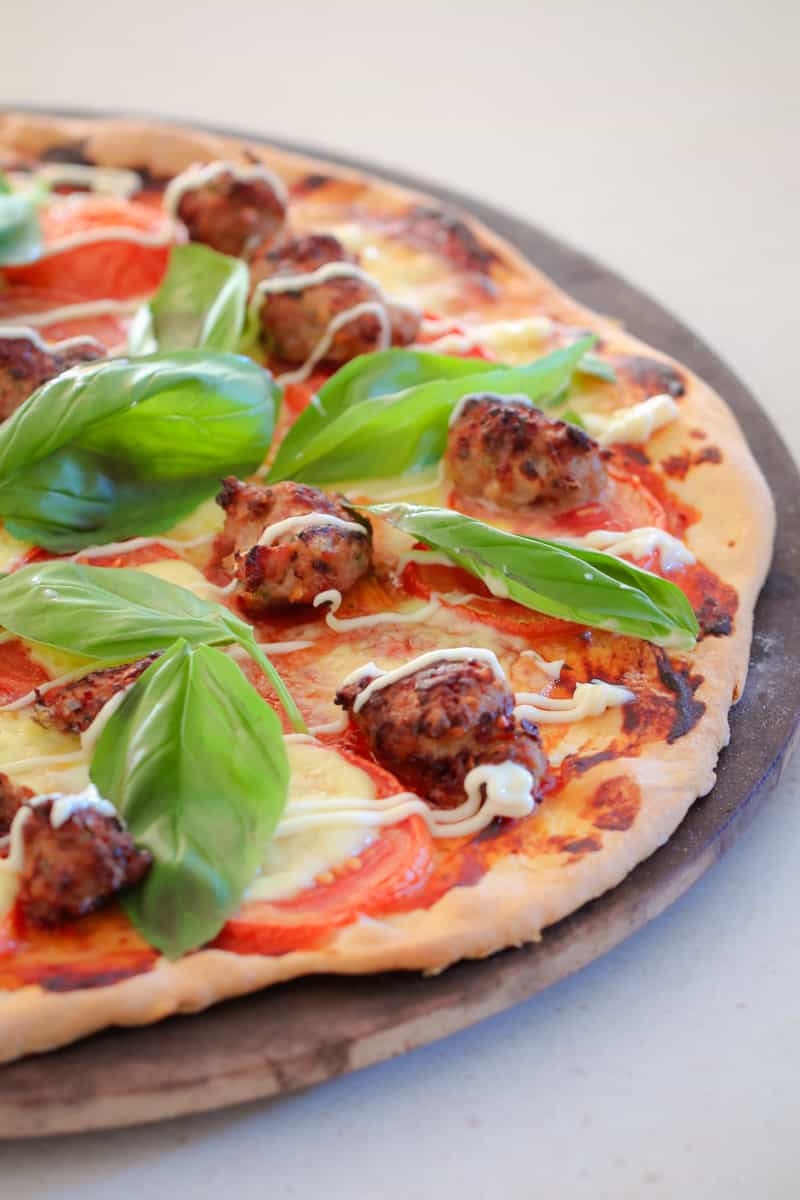 A pizza topped with meatballs tomato, basil and kewpie mayo.