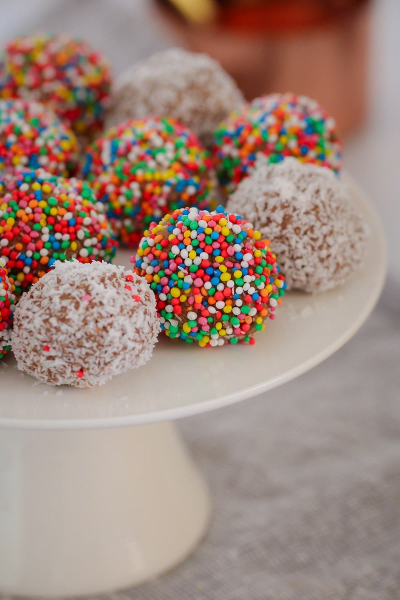 A close up of round balls, some rolled in coconut and some in coloured sprinkles