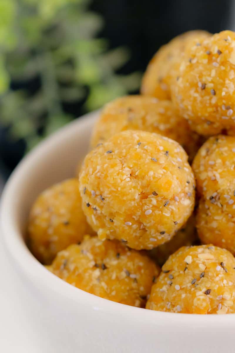 A close up of round Apricot Coconut Chia Bliss Balls in a white bowl.
