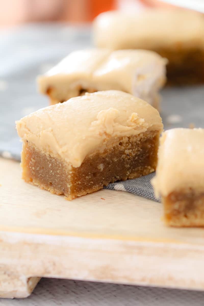 A close up of squares of slice topped with caramel frosting on a blue tea towel