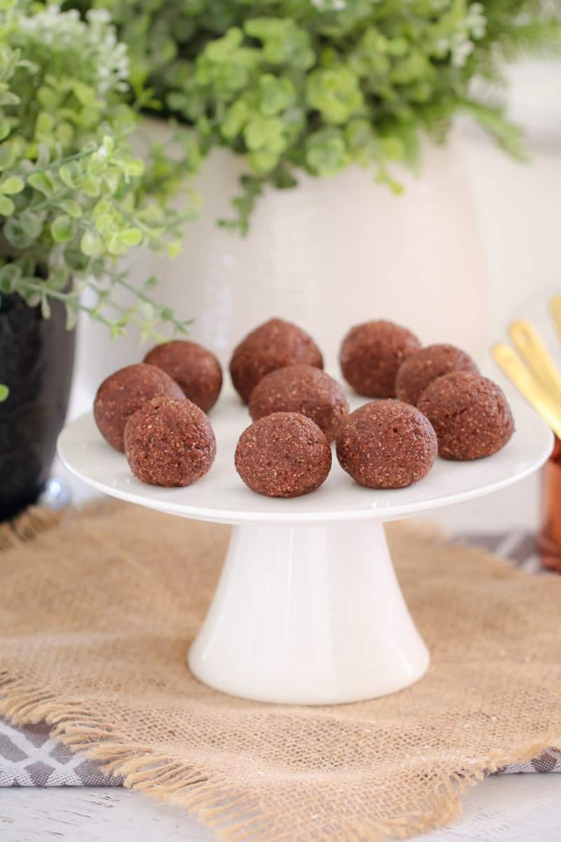 Ten chocolate bliss balls on a white cake stand