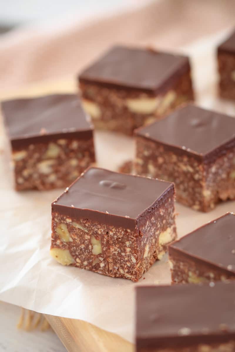 Squares of slice made with walnuts and crushed biscuits with a layer of chocolate on top.