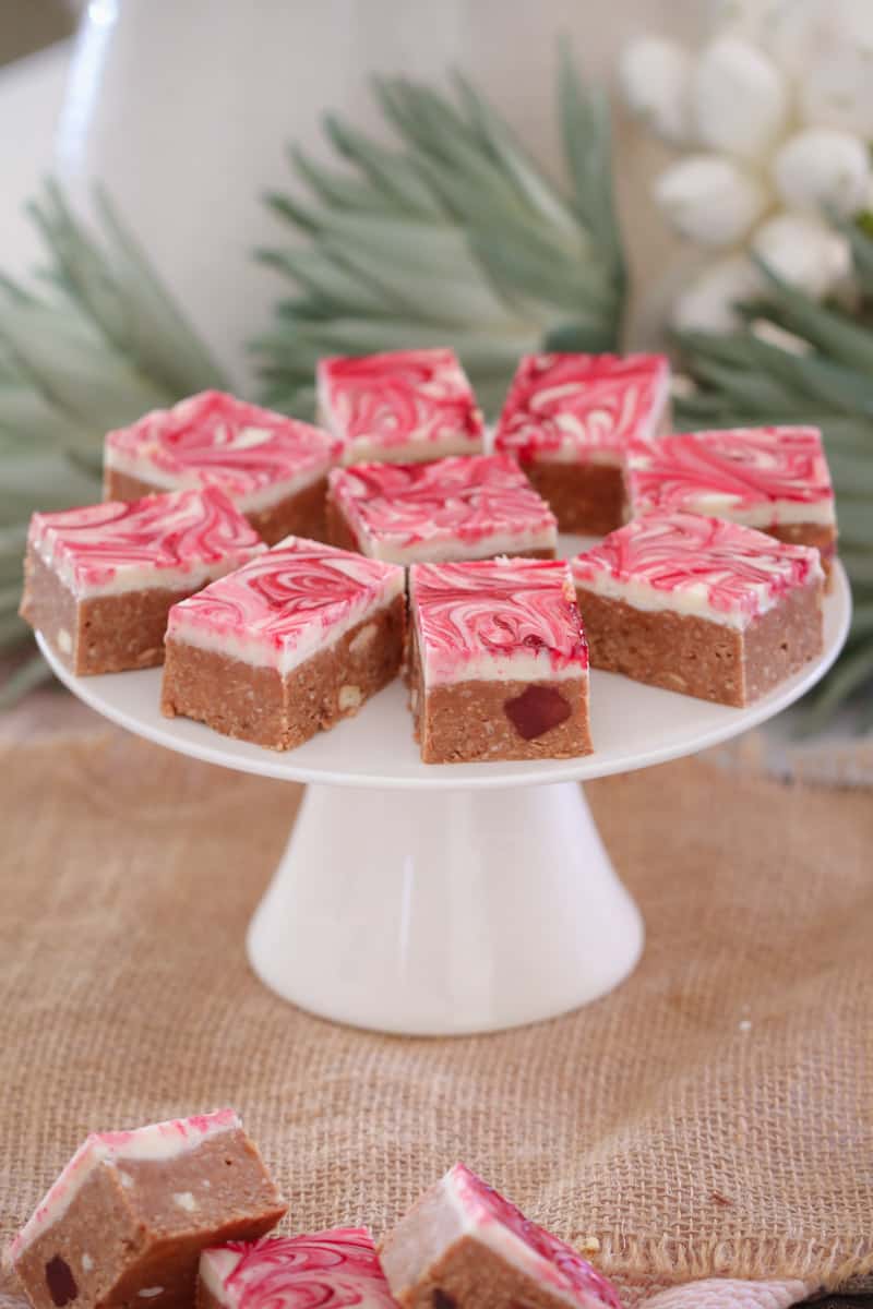 Pieces of pink and white chocolate slice on a white cake stand.