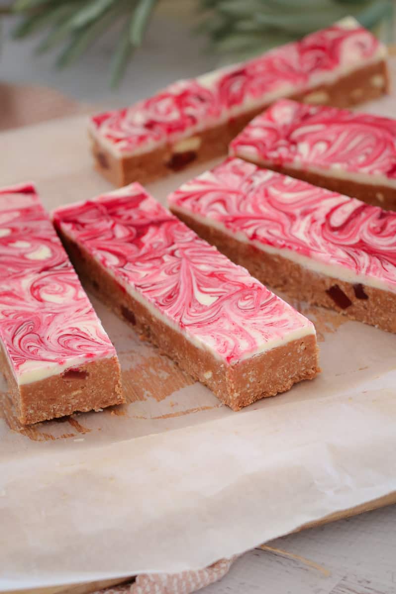 Pieces of slice with a pink and white swirled chocolate topping on a white plate