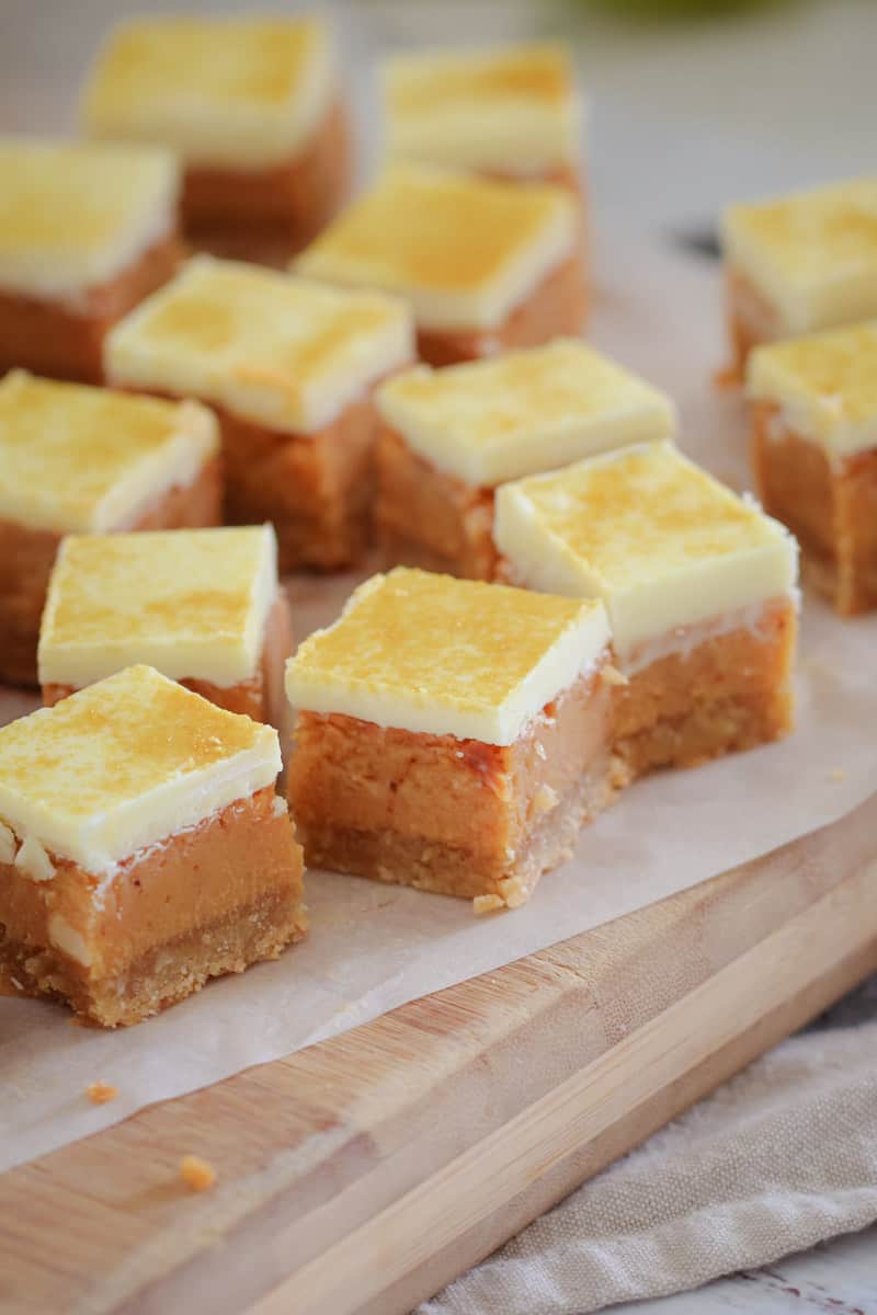 A pile of caramel slice squares served on a wooden board