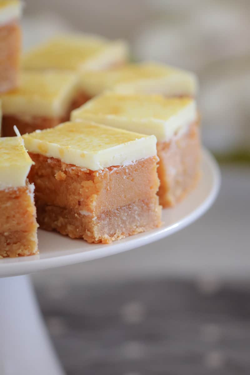 A close up of white chocolate topped squares of a golden caramel slice