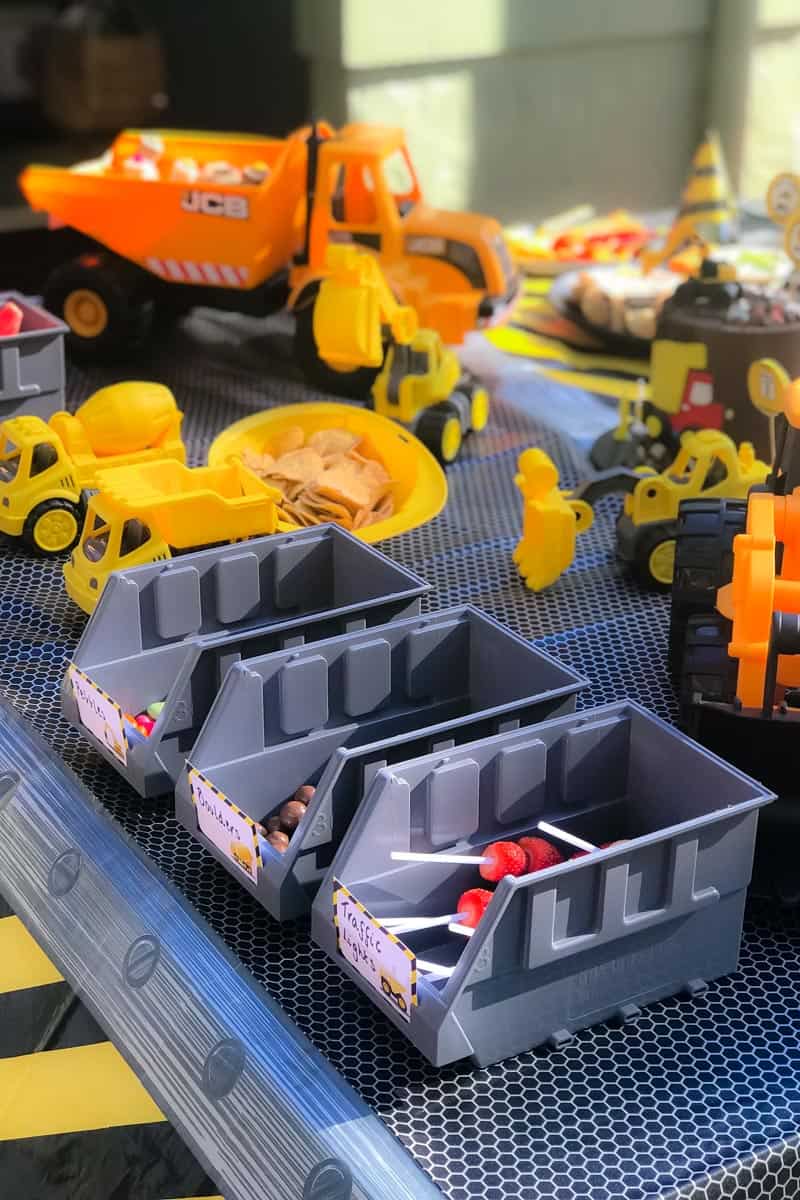 A close up of a toy trucks and trays filled with lollies for a Digger Party