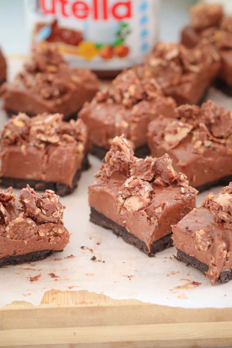 Squares of a rich chocolate cheesecake slice with crumbled hazelnuts and chocolate on top