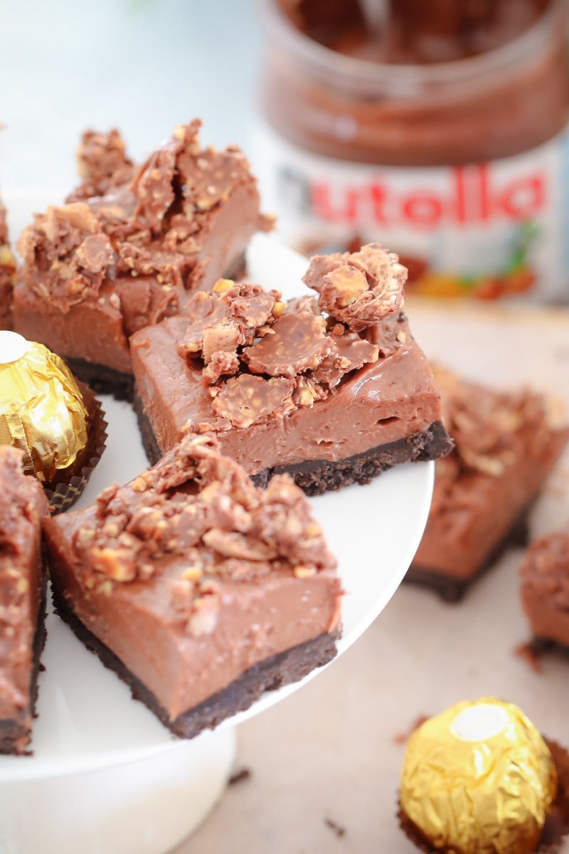 Squares of a rich mousse-like cheesecake, decorated with crumbled chocolates and a Ferror Rocher