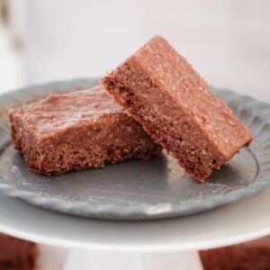 Two pieces of a coconut rough slice served on a grey plate