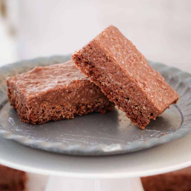 Two pieces of a coconut rough slice served on a grey plate