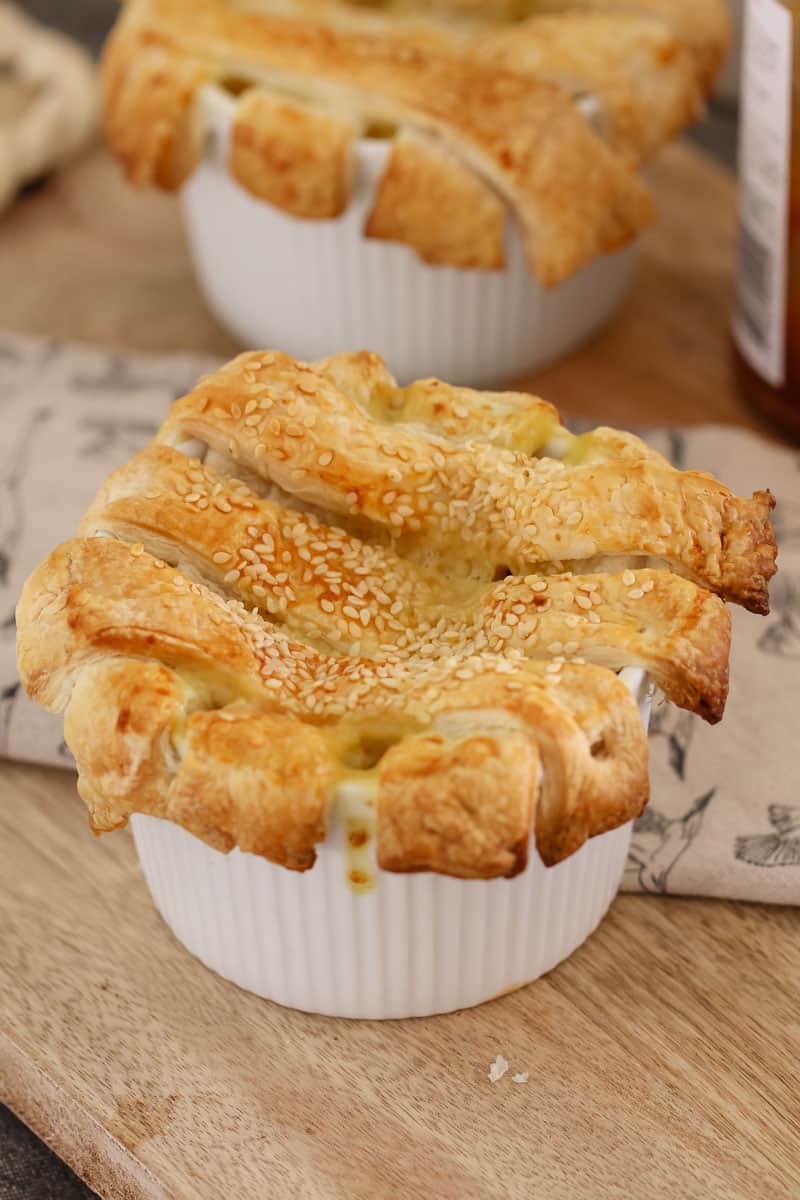 A small white ramekin of chicken and leek filling and a pastry lattice top overlapping the sides