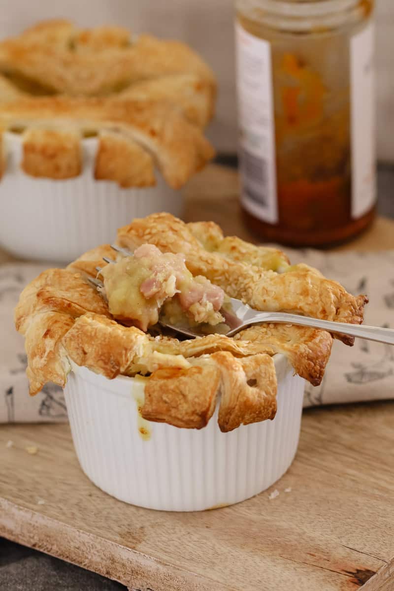 A forkful of chicken and leek pie in a small white ramekin and topped with a pastry lattice