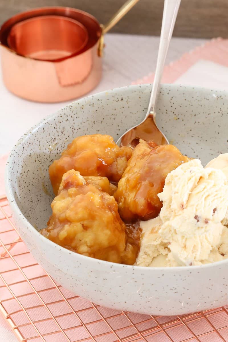 A spoon and bowl filled with golden dumplings and ice cream