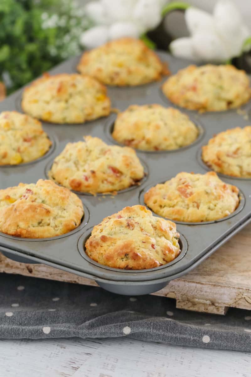 A muffin baking tray filled with savoury muffins on a wooden board